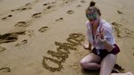 teen girl finishes writing "aloha" sand Stok Videosu (%100 T